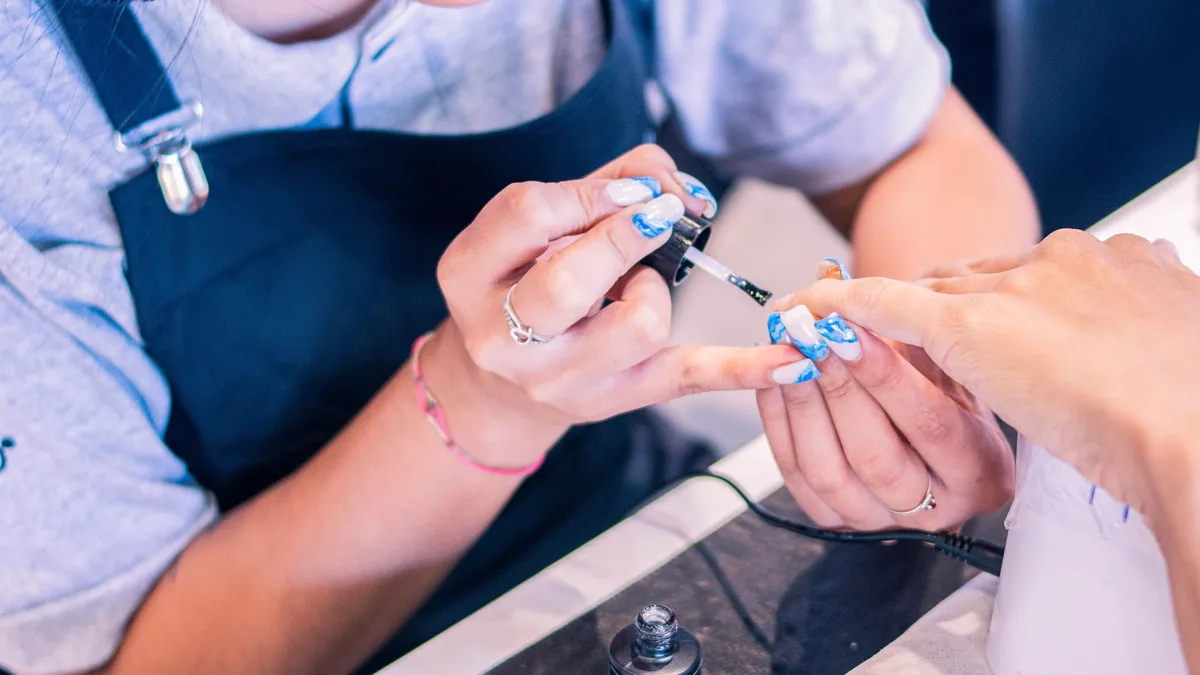 A person painting another person's fingernails with nail polish.